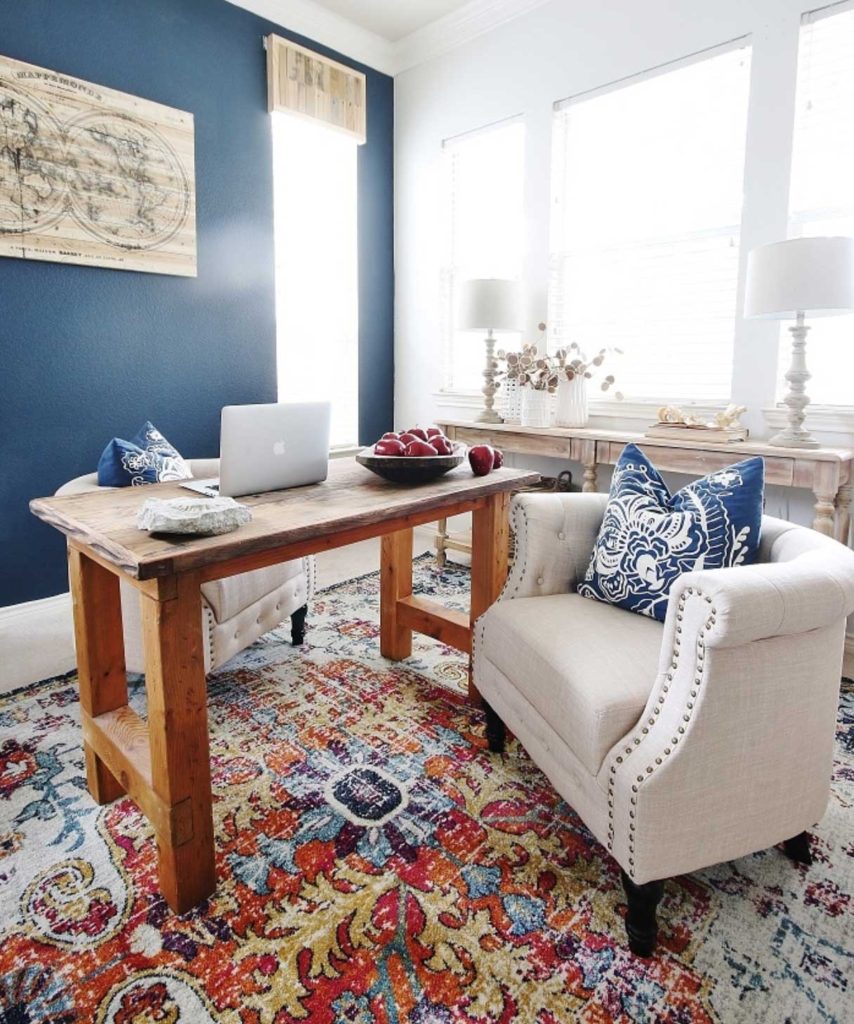 office with navy blue walls wood desk and white upholstered chair
