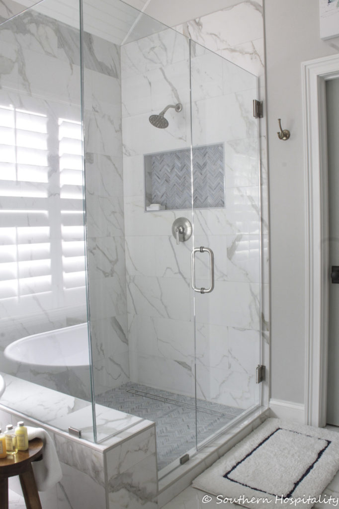 glass enclosed shower with marble walls
