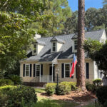 ivory colored cottage surrounded by trees