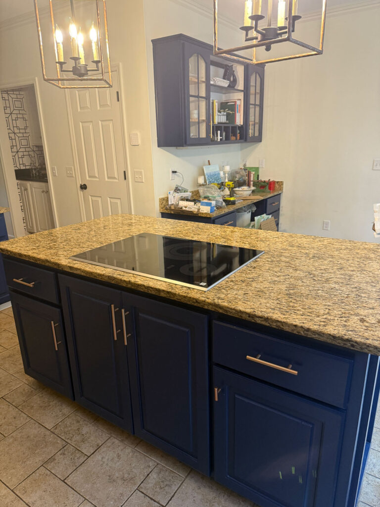 kitchen island with blue cabinets, brown granite counters and black induction cooktop