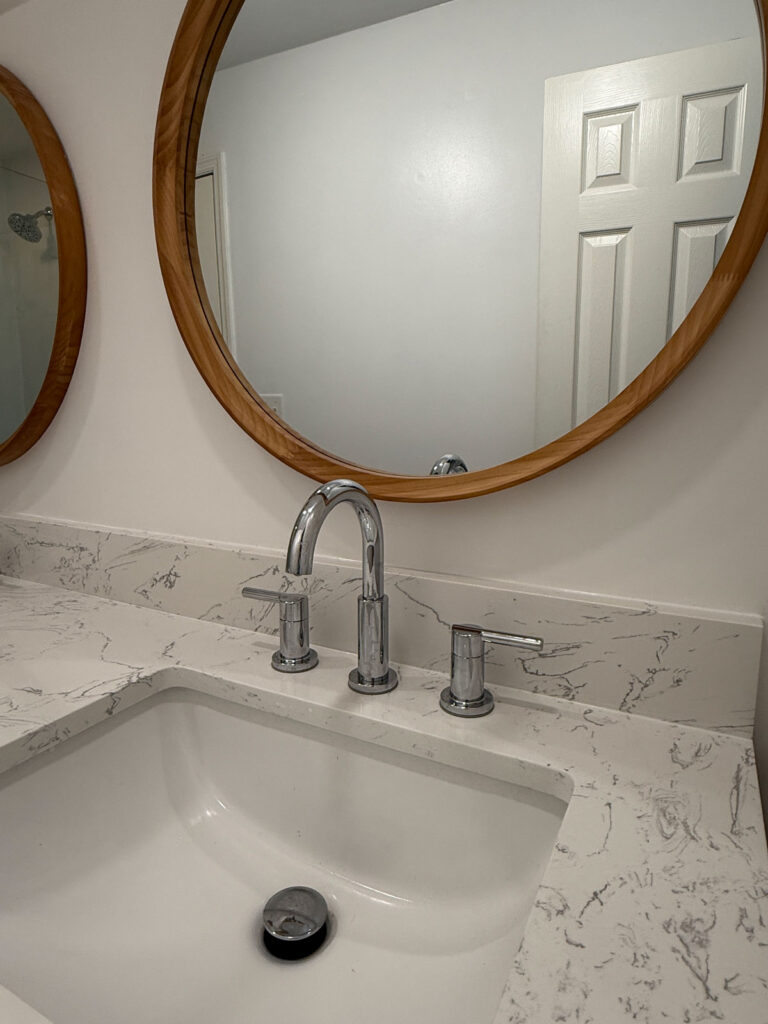 close up of bathroom sink with round mirror