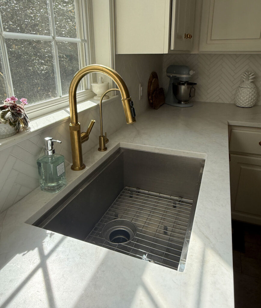 kitchen sink with white counters and gold fixtures