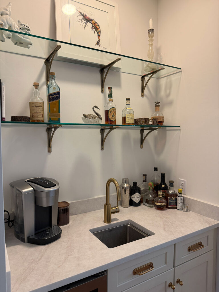 wet bar with brushed quartz counters and glass shelves