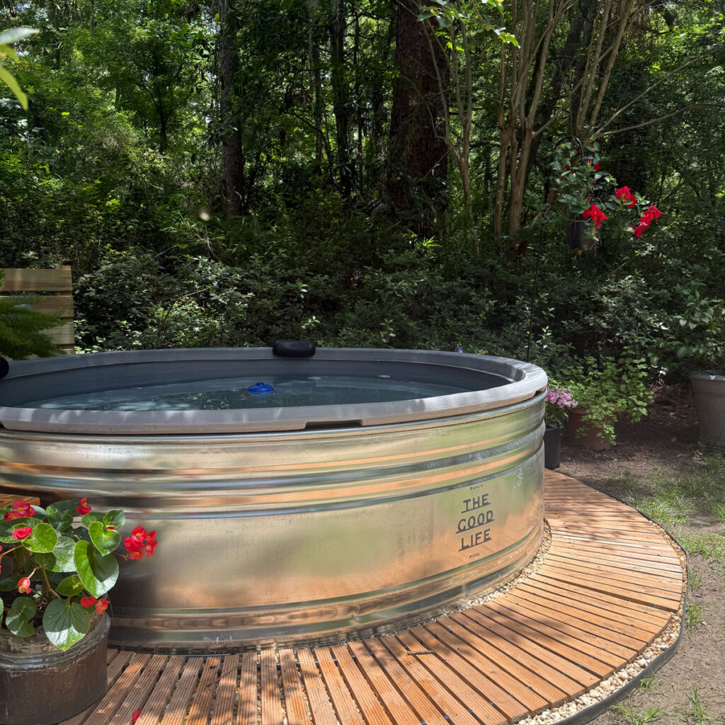beautiful stock tank pool with flowers and wood border walkway