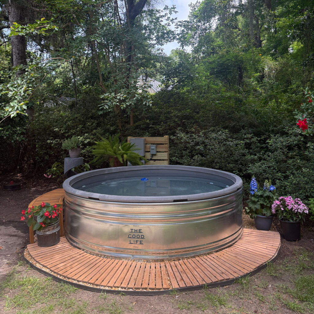 beautiful stock tank pool with flowers and wood border walkway
